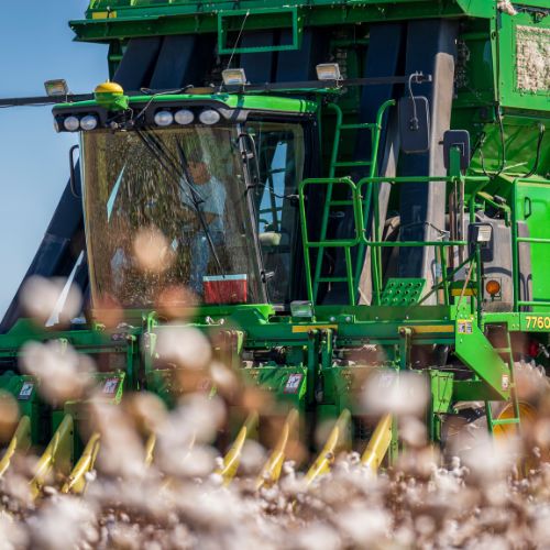 john deere cotton picker harvesting in field